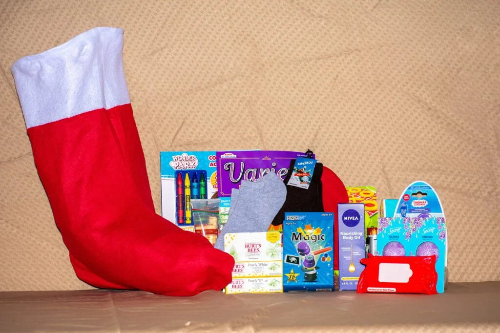 A red stocking and various items like crayons, socks, toiletries, and wipes are displayed. Related to northern plains reservation aid.