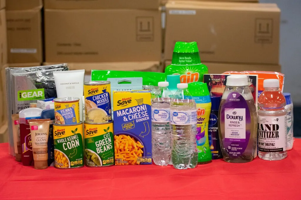 A variety of food items, beverages, and personal care products are displayed on a table. Northern Plains Reservation Aid is appropriate.