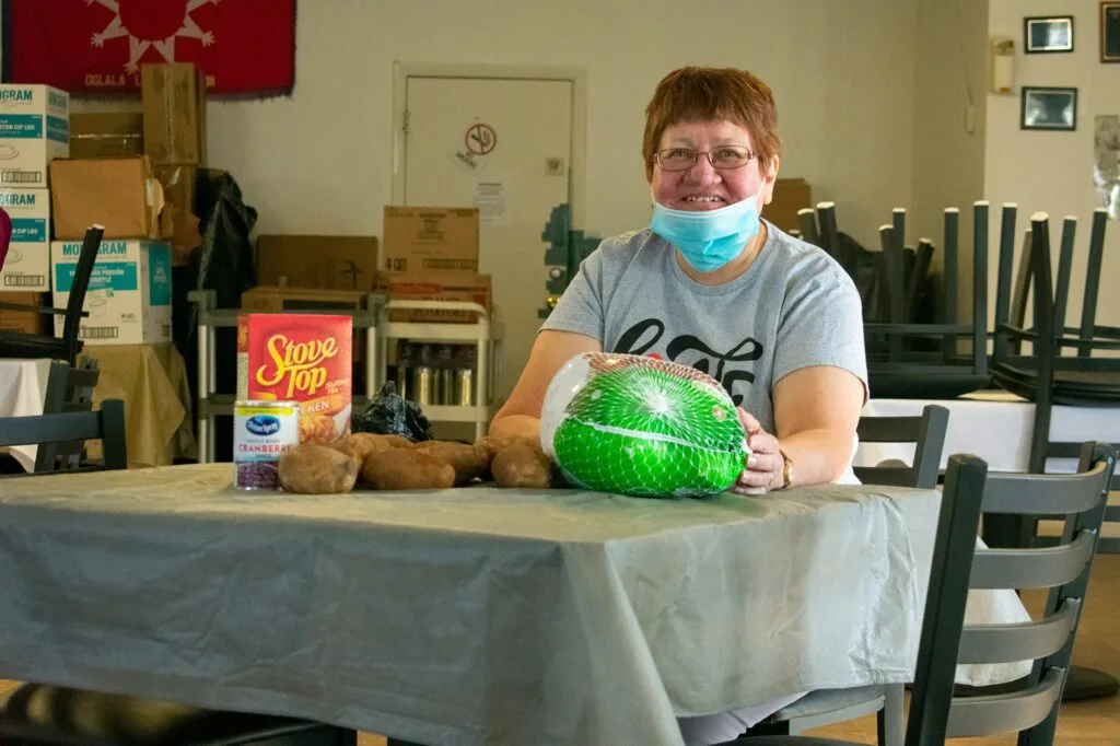 A person is sitting at a table with a turkey, potatoes, stuffing, and canned cranberries.