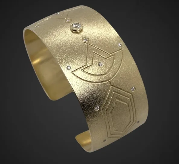 A gold cuff bracelet with geometric patterns and embedded gemstones.