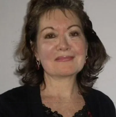 A woman with a black cardigan or blazer on and shoulder length hair smiling.