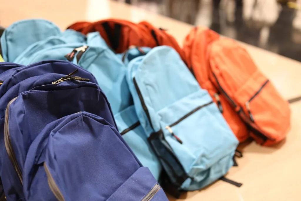 A variety of backpacks are arranged on a table.