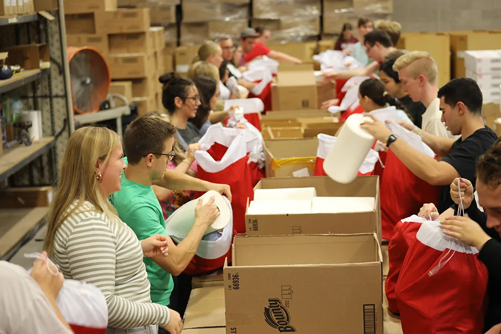 People are engaged in a community service activity, packing items in a warehouse setting.