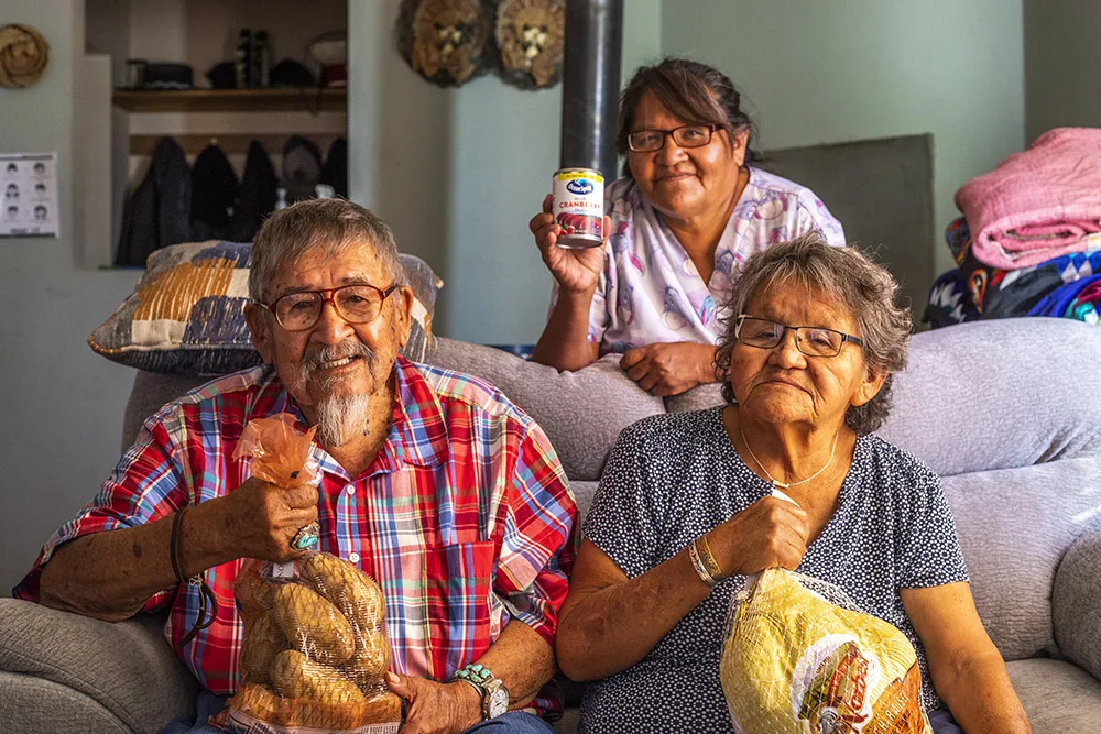 Three people smiling with grocery items, possibly related to southwest reservation aid.
