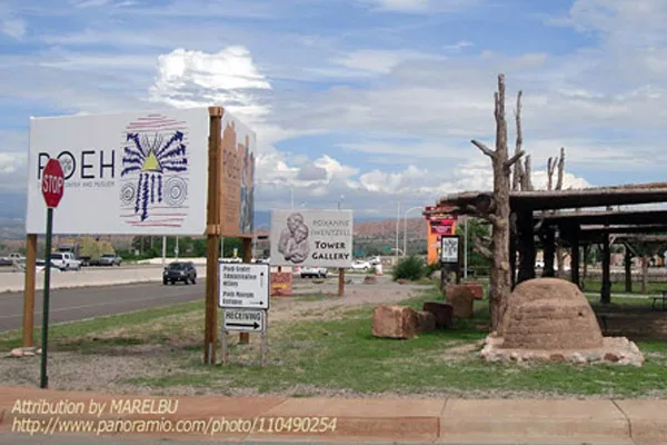 A roadside scene with signs for Poeh Cultural Center and Tower Gallery, located in Pojoaque Pueblo.