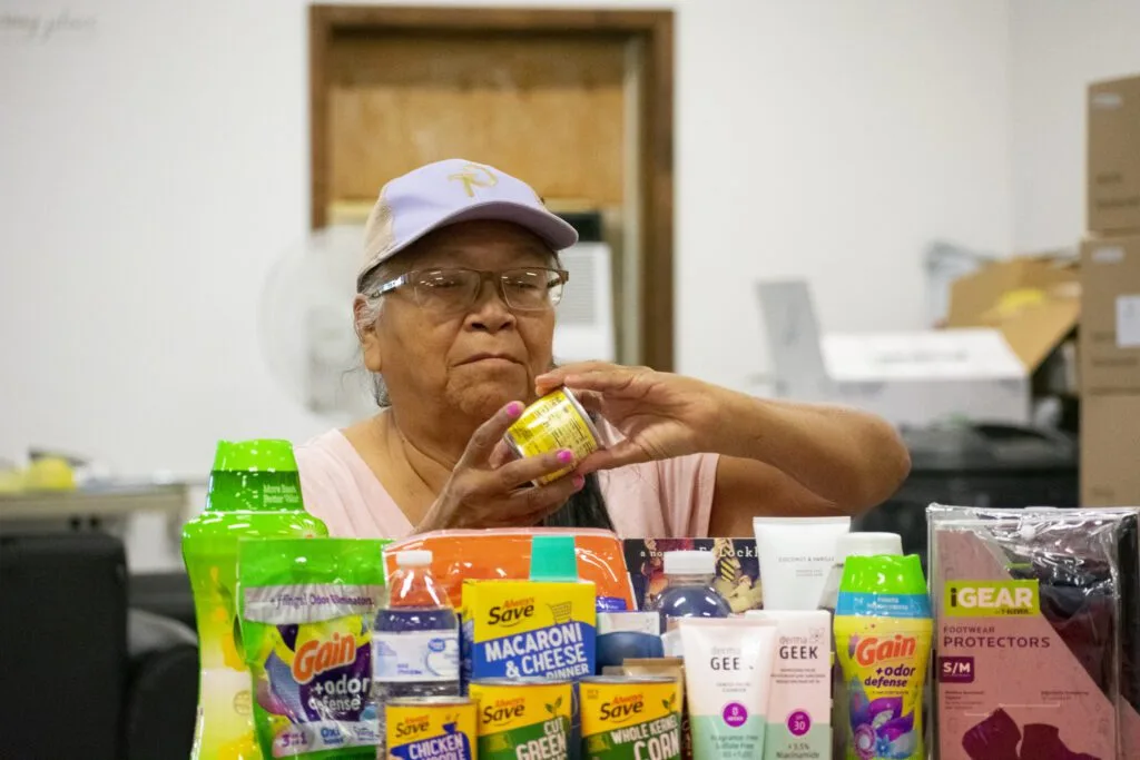 A person is handling a can among various household and personal care products.