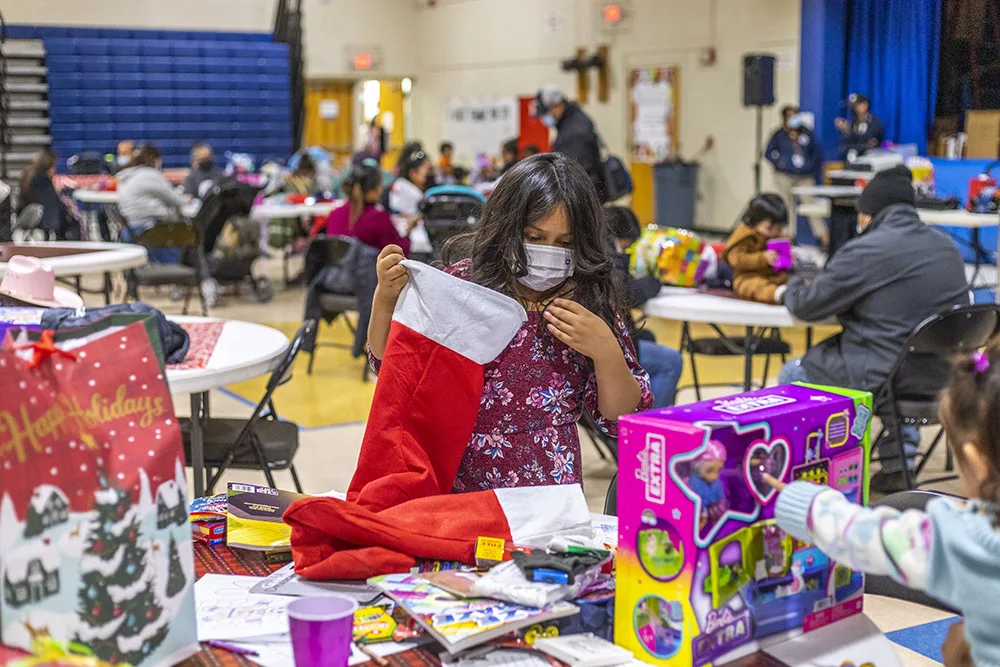 A group of people is gathered in a festive setting with toys and holiday decorations.