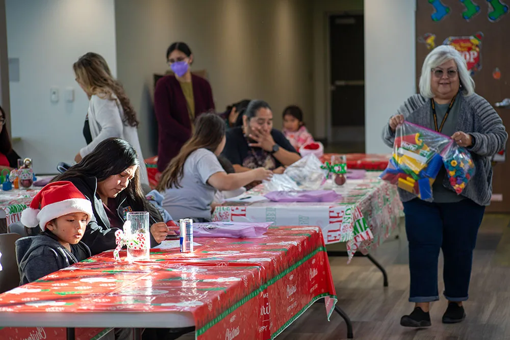 A holiday-themed gathering with people at decorated tables, some wearing festive clothes.