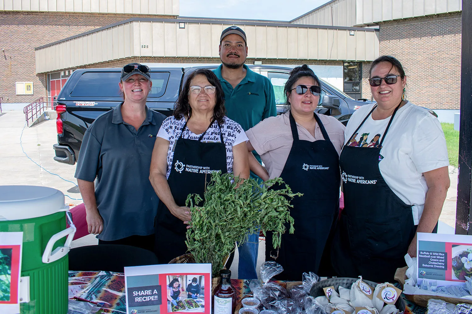 A group of people is standing at a booth promoting a native American nonprofit organization.