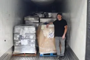 A person stands next to pallets of packaged goods in a truck.